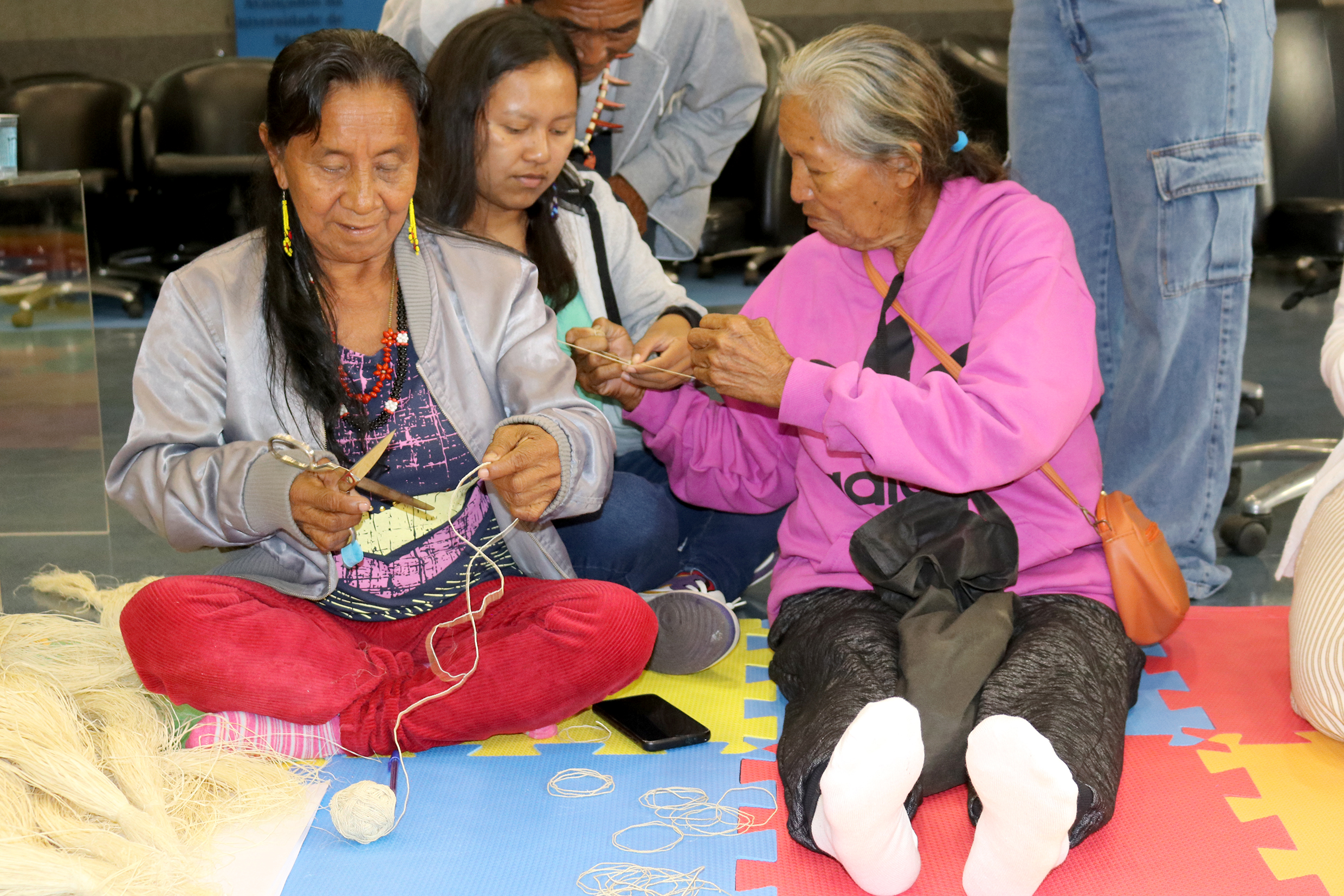 Maria Bidoca Baniwa, Larissa Fontes Baniwa e Bibiana Fontes Baniwa, ensinam como trançar o fio de palha para fazer artesanato